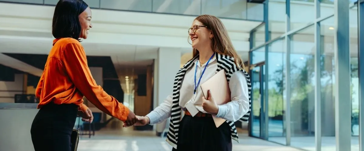 Two people meeting and shaking hands in an office atrium