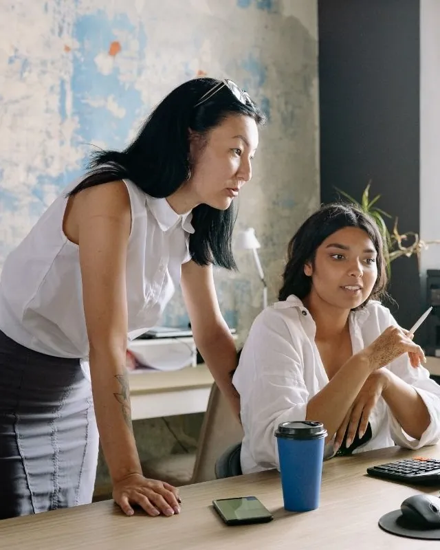 Two colleagues working through a problem together at a desk